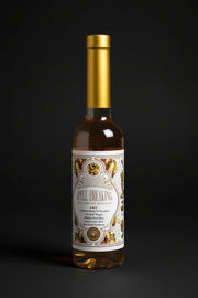 Two bottles of Spell Breaking cleansing water with gold caps on a black background