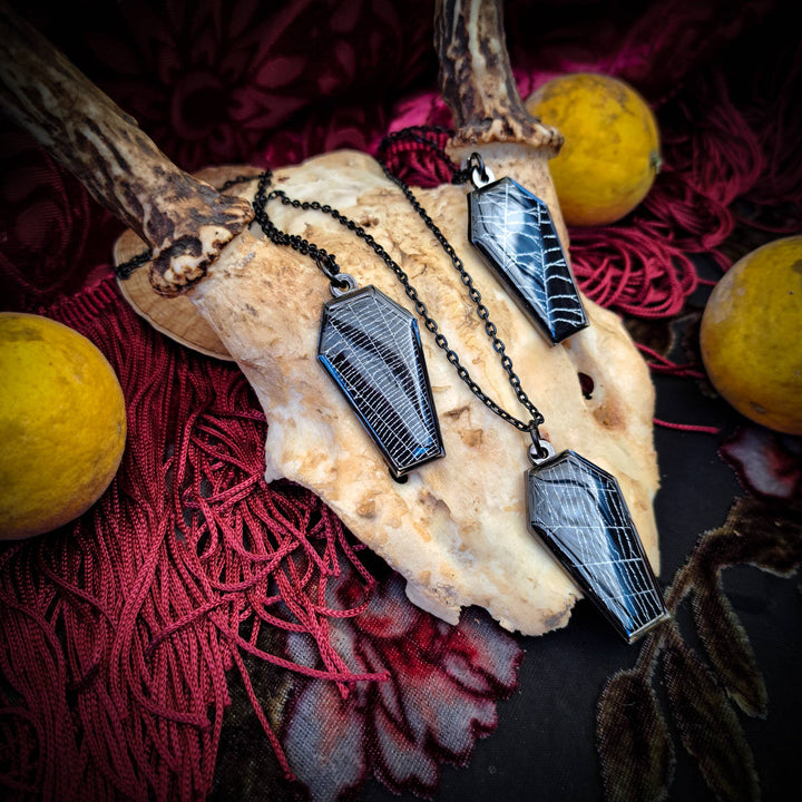 Black coffin-shaped necklace pendant containing genuine preserved spiderweb