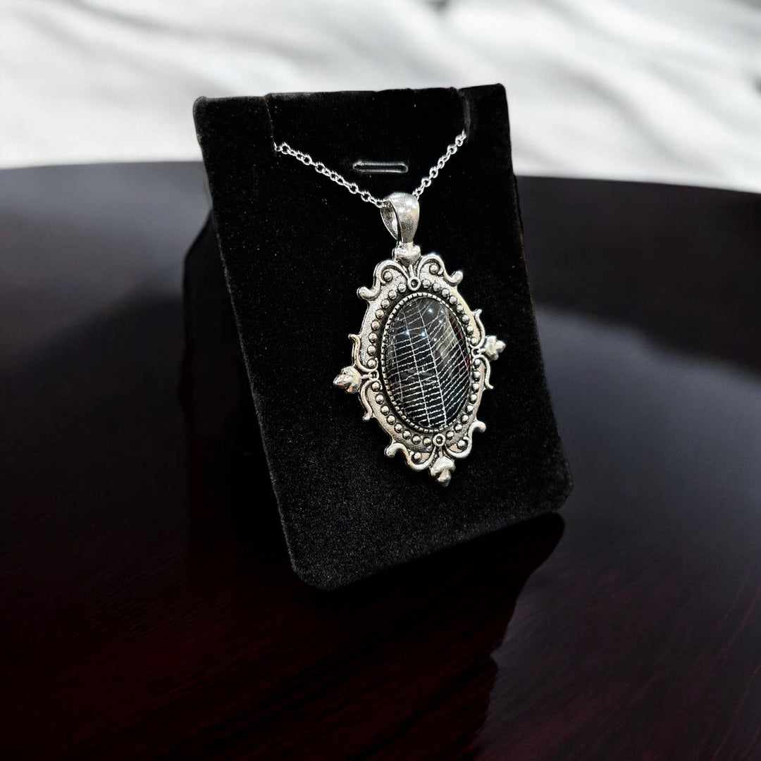 Close-up of silver-tone filigree cabochon with preserved spiderweb