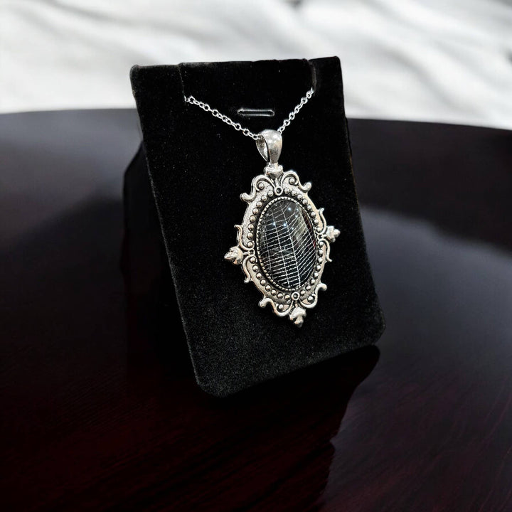 Close-up of silver-tone filigree cabochon with preserved spiderweb