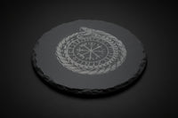 Round slate altar tile engraved with Nordic ouroboros and runic-style symbol used as a ritual surface.