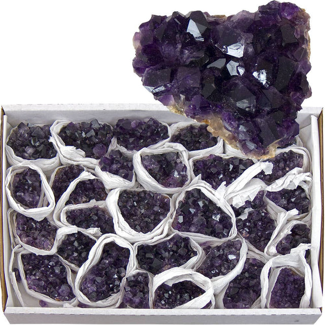 Box of amethyst crystals with a large amethyst geode on top