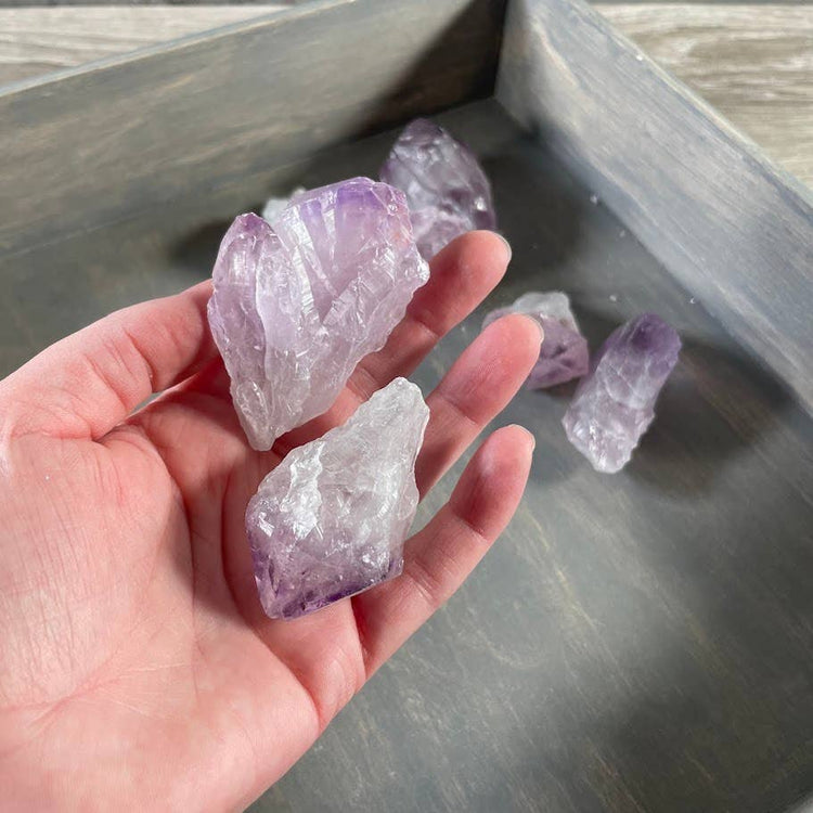 Hand holding amethyst crystals on a wooden surface