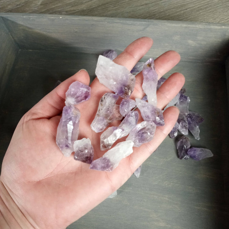 Hand holding purple crystal rocks on a metallic surface