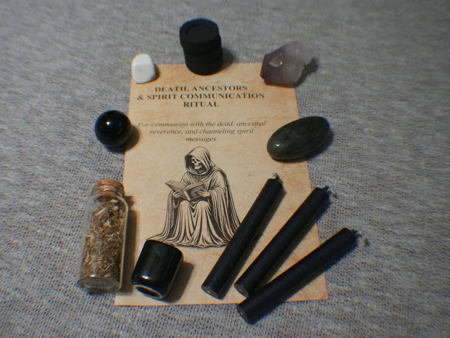 Witchcraft supplies including black candles, a small bottle, and a card on a textured surface
