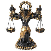 Decorative statue of a figure with a headdress, holding scales, on a white background