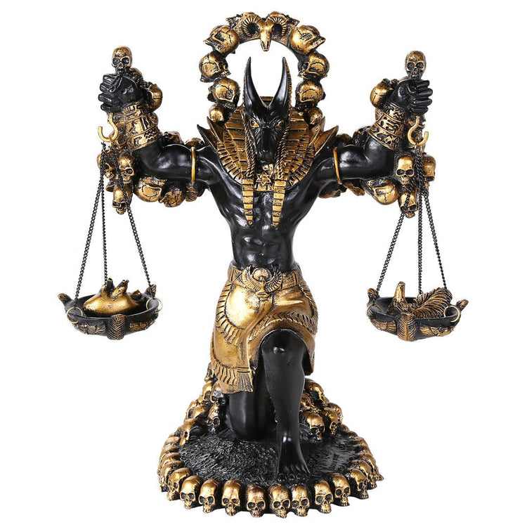 Decorative statue of a figure with a headdress, holding scales, on a white background