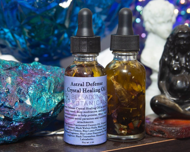 Two bottles of Astral Defense Crystal Healing Oil with droppers on a mystical background.