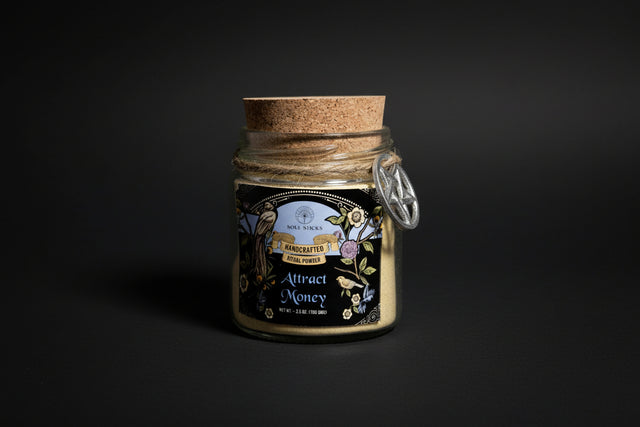 Jar of handcrafted ritual powder labeled 'Attract Money' with a cork lid on a white background.