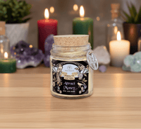 Jar candle with cork lid on a wooden surface with candles and decorative items in the background