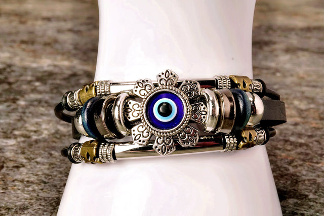 A multicolored bracelet featuring a central evil eye design with intricate patterns and beads, displayed on a white band.
