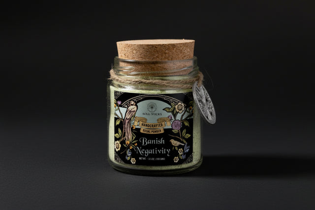 Jar of 'Banish Negativity' powder with decorative label and cork lid on a white background