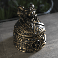 Decorative bronze bell with ram's head on a dark surface