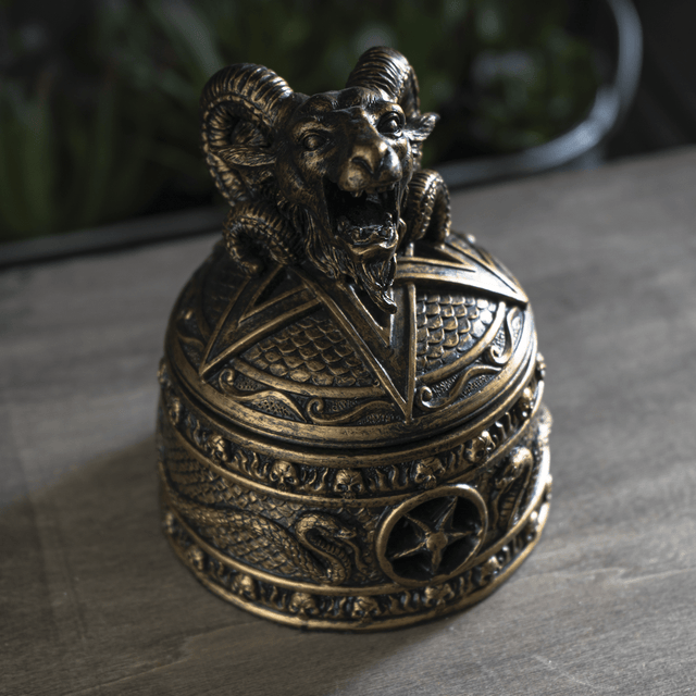 Decorative bronze bell with ram's head on a dark surface