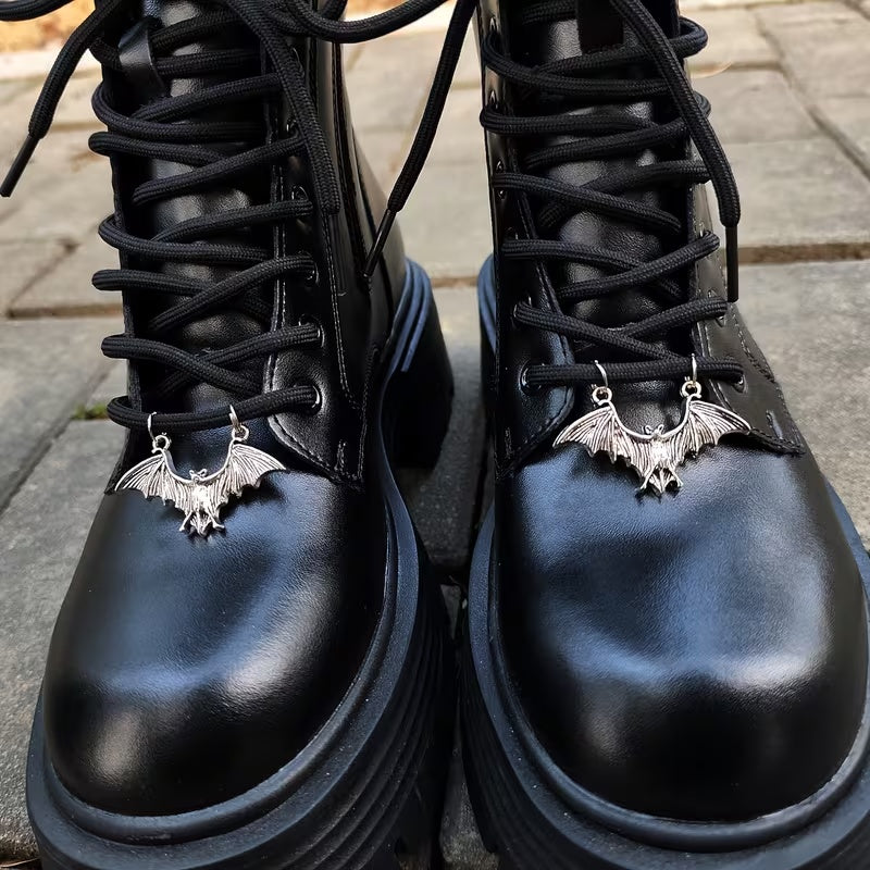 Pair of silver-tone bat boot charms attached across black boot laces