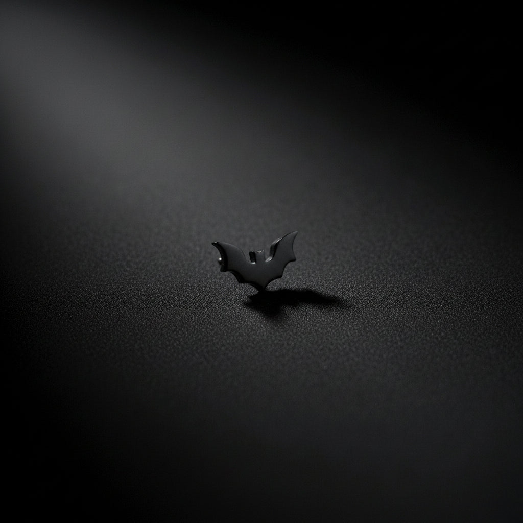 White ceramic sculpture of a face with a black bat earring on a dark background