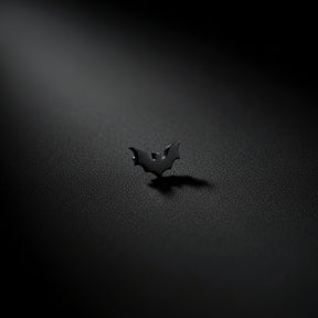 White ceramic sculpture of a face with a black bat earring on a dark background