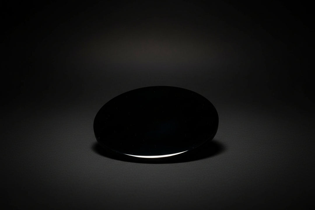 Hand holding a round polished dark mirror sold as black obsidian