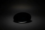 Hand holding a round polished dark mirror sold as black obsidian