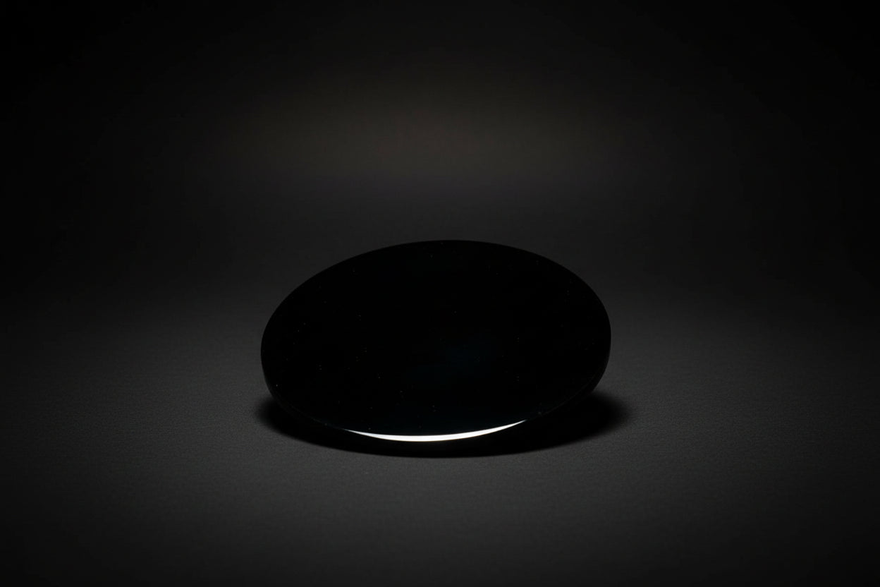 Hand holding a round polished dark mirror sold as black obsidian