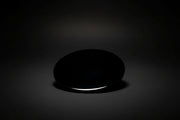 Hand holding a round polished dark mirror sold as black obsidian
