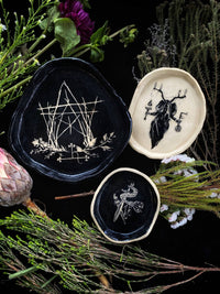 Three decorative plates with intricate designs on a dark background with greenery.