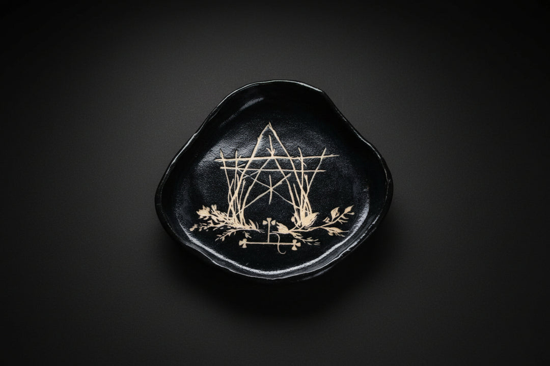 Hand holding a black sgraffito ceramic offering plate