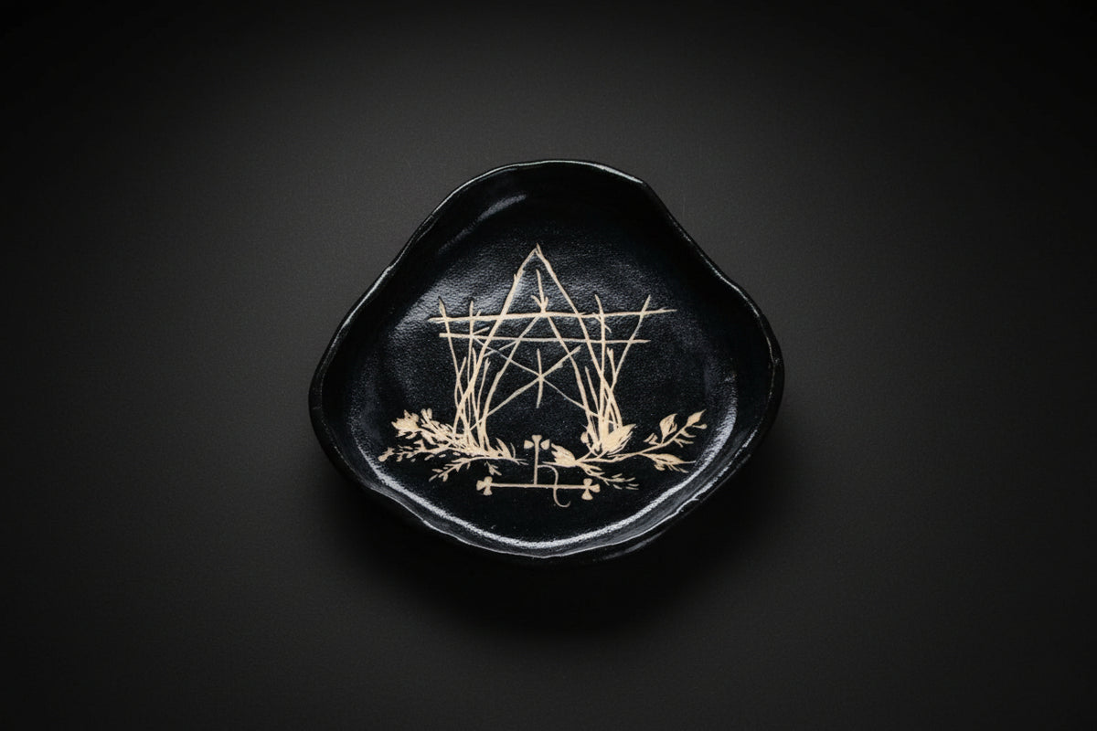 Hand holding a black sgraffito ceramic offering plate