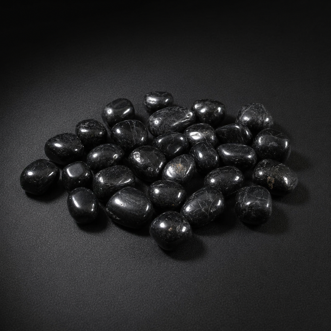 Polished Black Tourmaline tumbled stones with subtle natural inclusions on a matte black surface