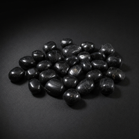 Polished Black Tourmaline tumbled stones with subtle natural inclusions on a matte black surface