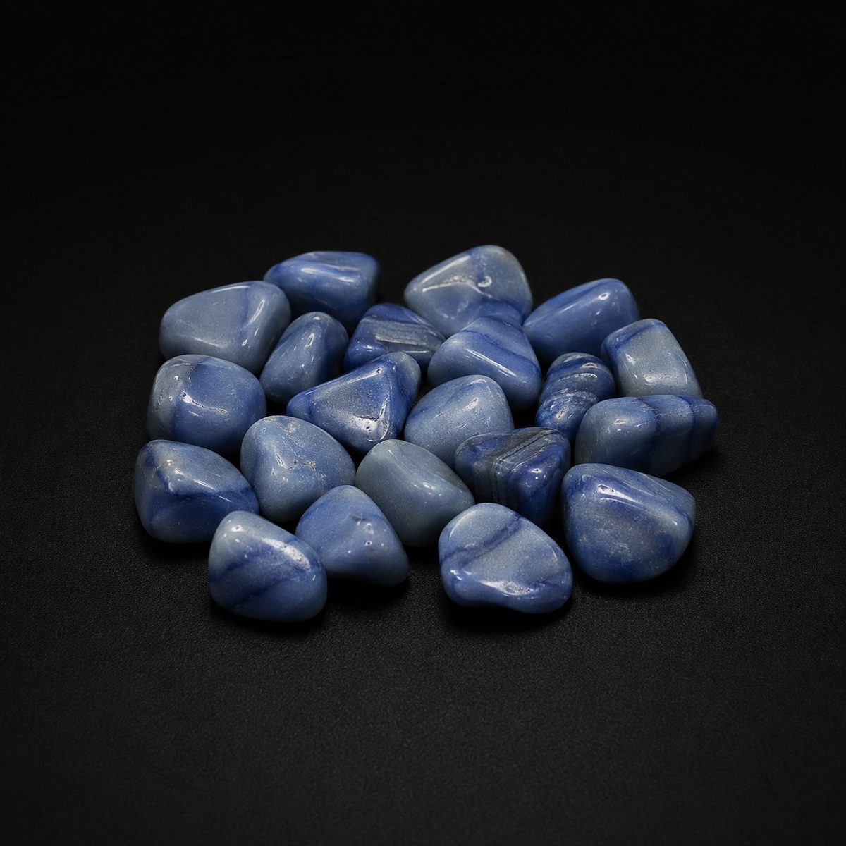 Polished blue stones sold as Blue Aventurine with cloudy blue banding on a matte black surface