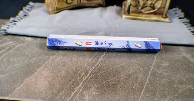 A pack of Blue Sage incense sticks displayed on a table with a cloth in the background.