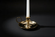 Gold candle holder with a white candle on a white background