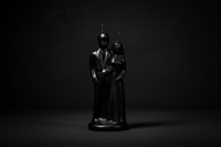 Black statue of a figure holding a child on a white background