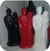 Three candles shaped like people, one black, one red, and one white, on a white background.