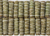 Multiple bundles of dried herbs tied with white string on a white background