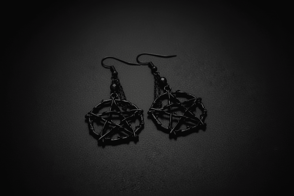 Black pentagram earrings on a black background.