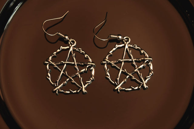 silver wood like pentacle earrings on dark background