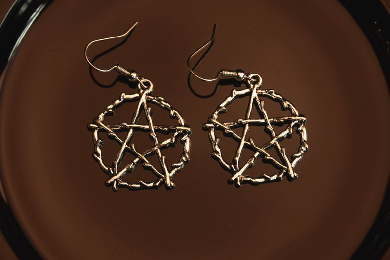 silver wood like pentacle earrings on dark background