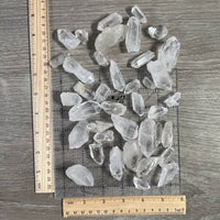 Clear crystal stones on a wooden surface with a ruler for scale.