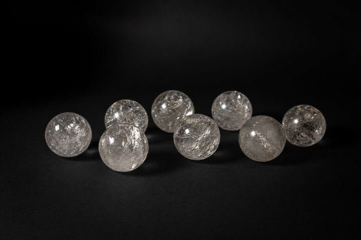 Eight polished Clear Quartz spheres with varied internal veils and fractures on black