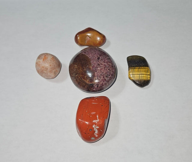 Collection of polished stones on a white sheet of paper with a wooden surface.