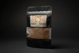 Black coffee bag labeled 'Crossroads Dirt' by LAMIA next to a decorative skull.