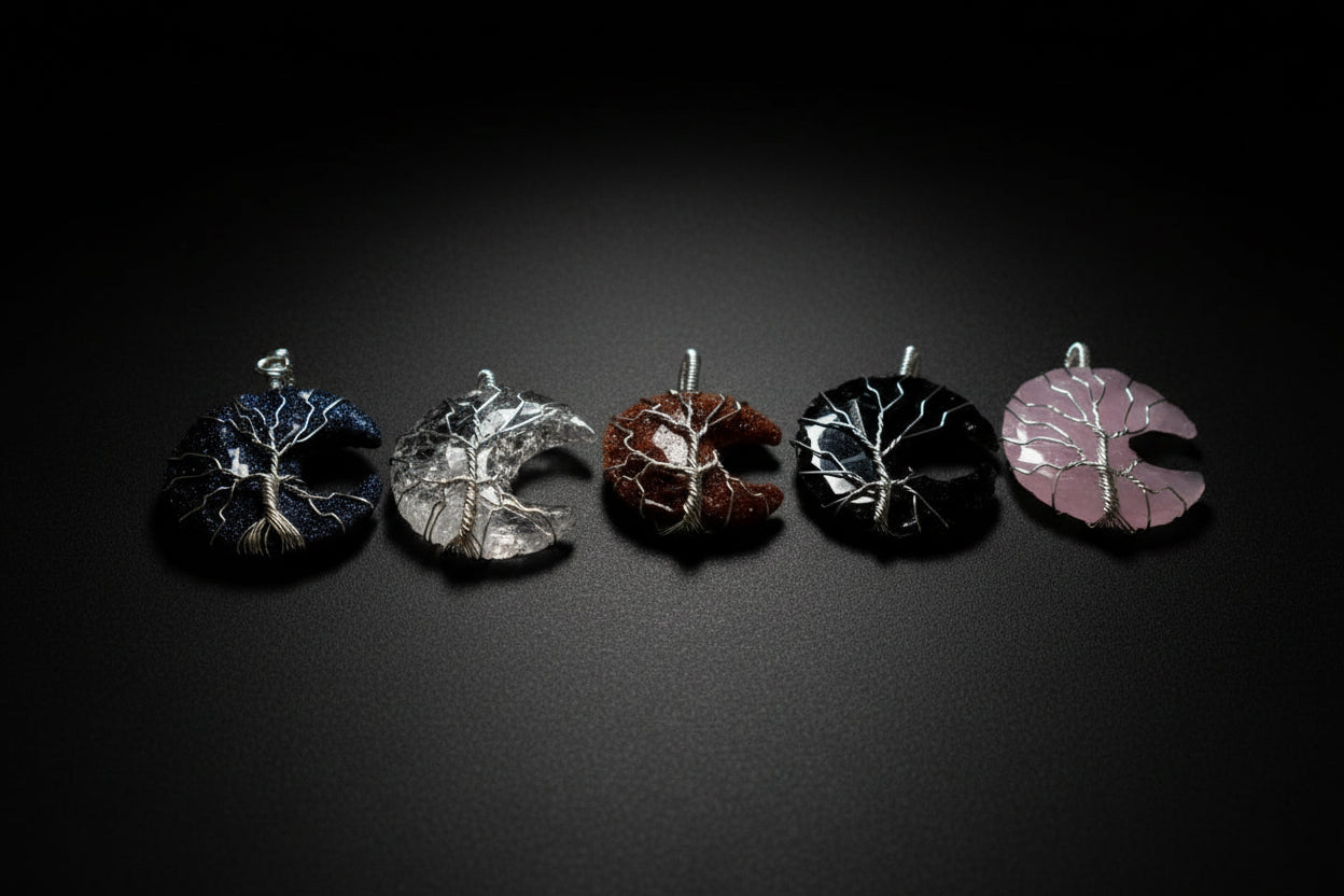 Hand holding five moon-shaped jewelry pieces against a natural background