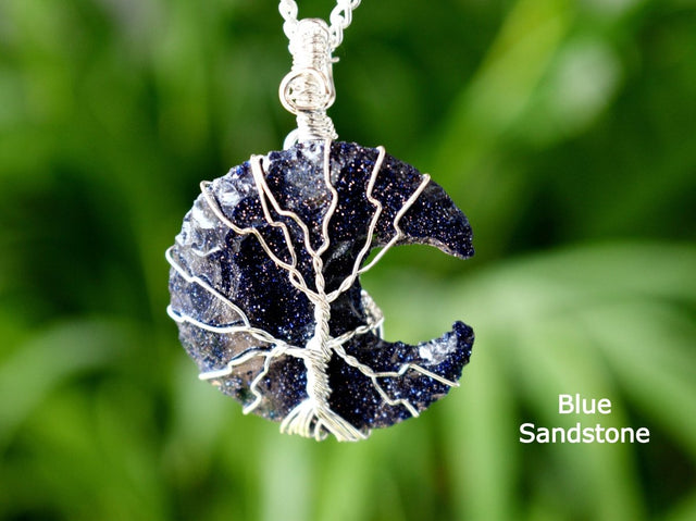 Blue sandstone pendant with silver wire wrapping on a blurred green background