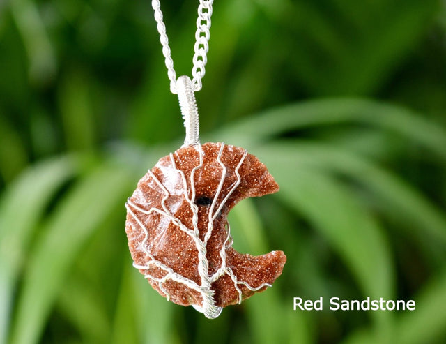 Red sandstone necklace with white veins on a blurred green leaf background