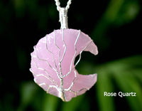 Rose Quartz moon-shaped pendant with silver wire detailing on a dark background