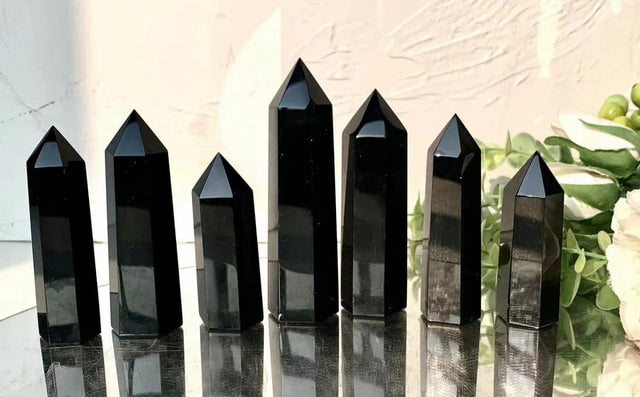 Black crystal points on a reflective surface with 'smcrystalwholesale.com' text above.