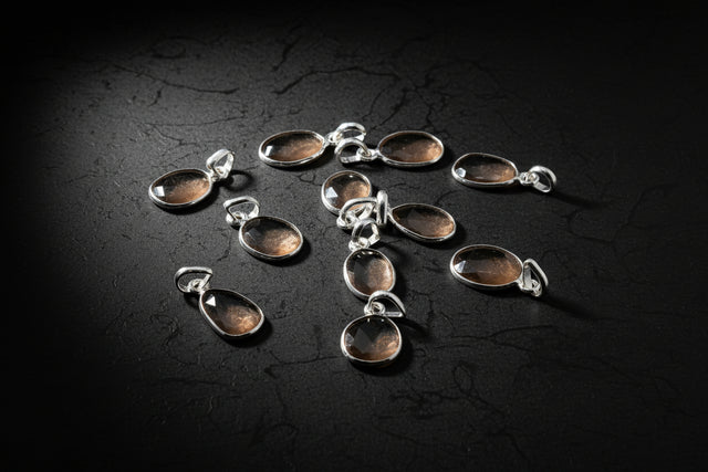 Collection of silver pendants with brown stones on a black background