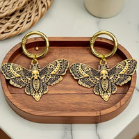 Pair of gold-tone death head moth boot charms showing skull-wing details and round clip rings